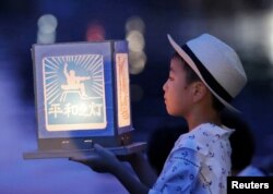 Seorang anak laki-laki memegang lentera kertas untuk mengenang para korban bom atom 1945 pada hari peringatan 74 tahun pengeboman di Nagasaki, Jepang barat. (Foto: Kyodo via Reuters)