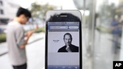 A man holds an iPhone 4 displaying an obituary of Apple co-founder Steve Jobs outside an Apple Store in downtown Shanghai October 6, 2011.