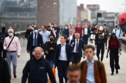 Commuters walk across the London Bridge during the morning rush hour, in London, Britain, Sept. 21, 2020.