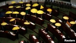 Pro-democracy lawmakers open yellow umbrellas, symbol of the Occupy Central movement, during a Legislative Council meeting as a gesture to boycott the government in Hong Kong, January 7, 2015.