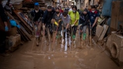 Relawan dan warga membersihkan kubangan lumpur dari jalanan di daerah yang terdampak banjir di Paiporta, Valencia, Spanyol timur. 