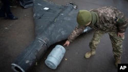 A Ukrainian officer shows a thermobaric charge of a downed Shahed drone launched by Russia in a research laboratory in an undisclosed location in Ukraine, Nov. 14, 2024. 