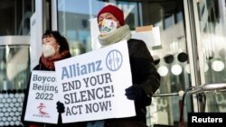 Seorang demonstran dirantai ke gedung Allianz memegang poster saat protes warga Tibet menentang Olimpiade Musim Dingin Beijing, di Berlin, Jerman, 21 Januari 2022. (Foto: REUTERS/Hannibal Hanschke)