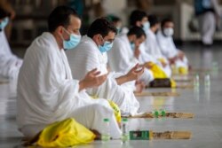 In this photo released by the Saudi Media Ministry, a limited numbers of pilgrims pray in the first rituals of the hajj, as they keep social distancing to limit exposure and the potential transmission of the coronavirus, at the Grand Mosque