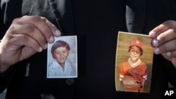 FILE - A plaintiff in a sex abuse settlement with the Roman Catholic Archdiocese of Los Angeles, holds up pictures of himself when he was a child during a news conference to announce details of a nearly $10 million settlement of their lawsuits against the Archdiocese of Los Angeles.