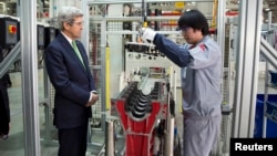 U.S. Secretary of State John Kerry (L) looks on as an engine is built during a tour of the Foton Cummins Engine plant in Beijing February 15, 2014. Kerry toured the plant and made remarks on climate change cooperation between the United States and China. 