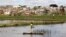 FILE - A man travels in a boat to fish in a pond in the outskirts of the capital Antananarivo, Madagascar.
