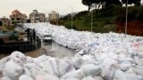 A van drives past piles of wrapped garbage blocking a newly-opened road in the town of Jdeideh northeast of Beirut, Lebanon.