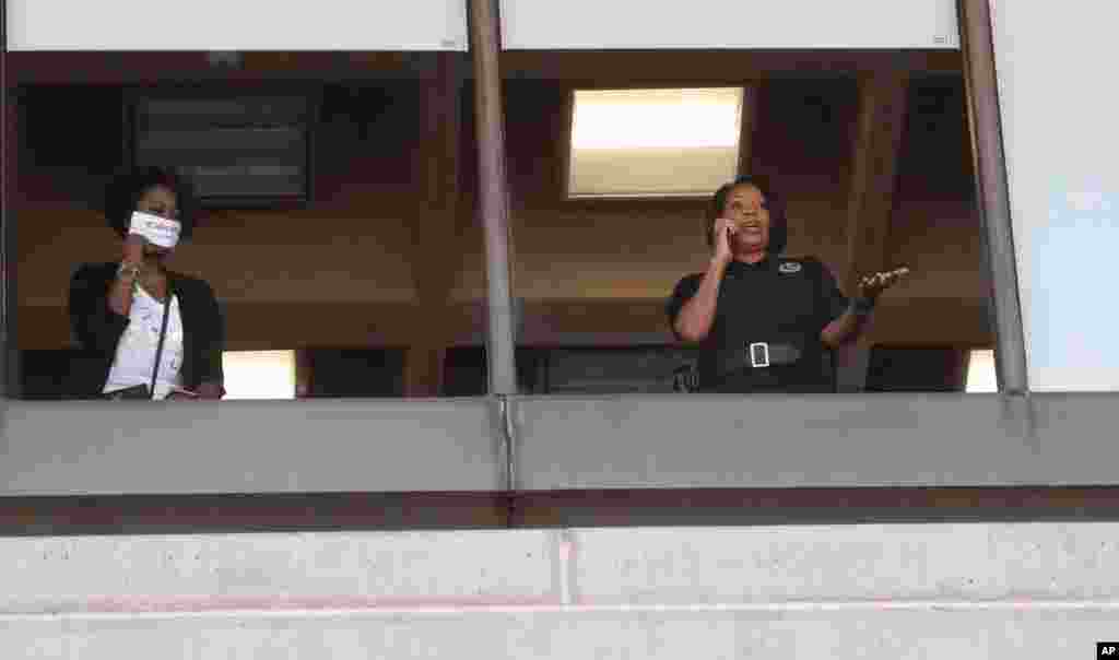 La jefa de la polic&#237;a de Dallas, Renee Hall, a la derecha, mira desde una ventana mientras los manifestantes se re&#250;nen frente al Ayuntamiento de Dallas, el s&#225;bado.