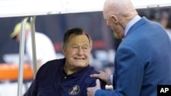 FILE - Former President George H.W. Bush talks with Houston Texans owner Bob McNair before a National Football League game between the Texans and the Cincinnati Bengals in Houston, Nov. 23, 2014.
