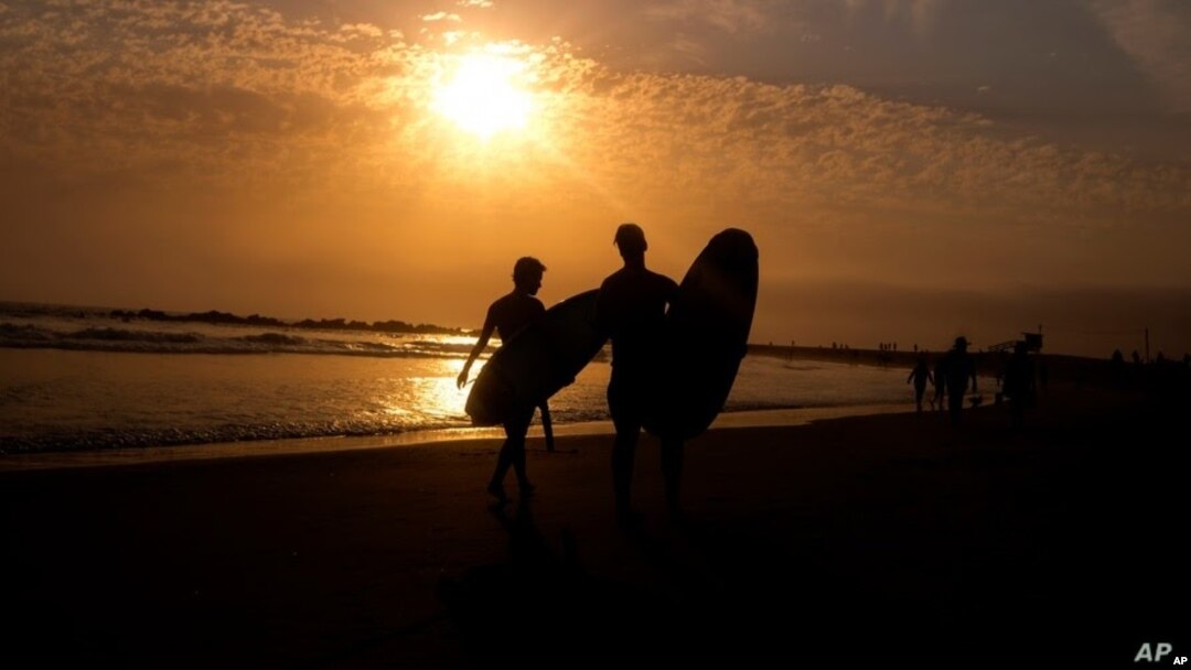 La silueta de dos surfistas se aprecia en esta foto de un atardecer en la playa Venice, de Los Angeles, el 16 de junio del 2021.