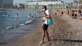 A man wearing a protective face mask carries a dog as he enjoys the sunny weather at Barceloneta beach, amid the coronavirus disease (COVID-19) outbreak, in Barcelona, Spain, May 21, 2020