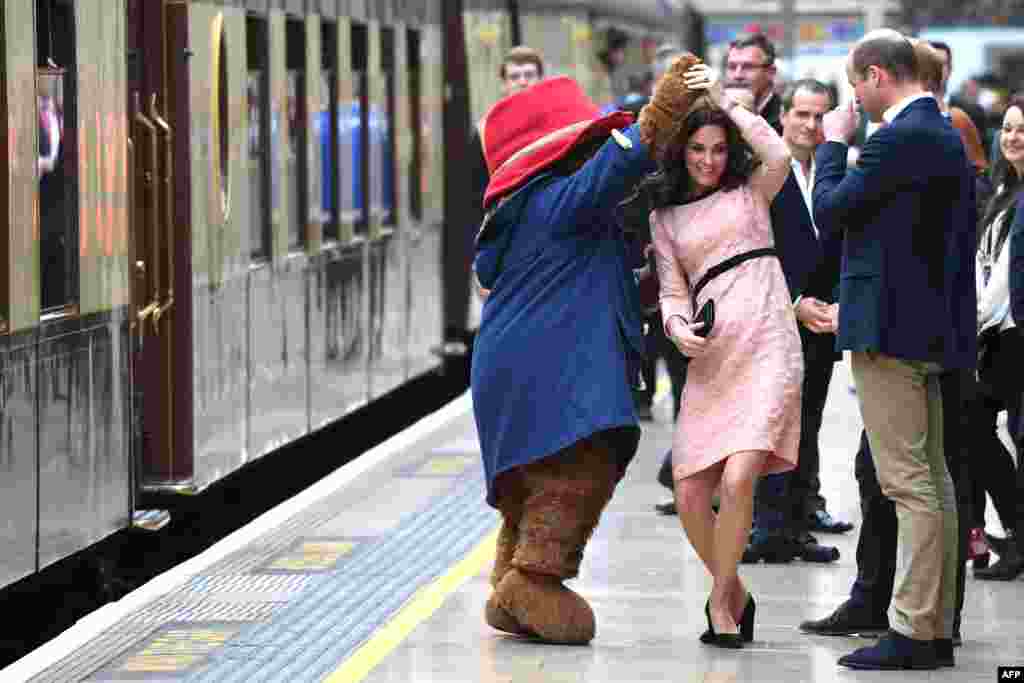 Britain&#39;s Catherine, Duchess of Cambridge, (C) dances with a person in a Paddington Bear outfit by her husband Britain&#39;s Prince William, Duke of Cambridge, as they attend a charities forum event at Paddington train station in London.