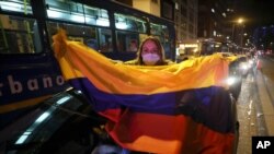 Una partidaria del expresidente Álvaro Uribe sostiene una bandera nacional mientras protesta por la decisión de la Corte Suprema de colocar a Uribe bajo arresto domiciliario mientras avanza una investigación de manipulación de testigos en su contra.