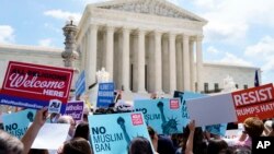 Protesters hold up signs and call out against the Supreme Court ruling upholding President Donald Trump's travel ban outside the the Supreme Court in Washington, Tuesday, June 26, 2018. (AP Photo/Carolyn Kaster)