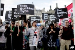 Demonstrators take part in a protest organized by the Stop the War coalition against the British government carrying out airstrikes on targets in Syria, in Parliament Square, London, April 16, 2018.