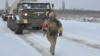 Pripadnik Ukrajinskih oružanih snaga korača ispred samohodnog višecevnog raketnog bacača tokom vežbi u regionu Kerson, Ukrajina, 1. februara 2022. (Foto: Ukrajinske oružane snage via Rojters)