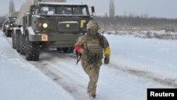 Pripadnik Ukrajinskih oružanih snaga korača ispred samohodnog višecevnog raketnog bacača tokom vežbi u regionu Kerson, Ukrajina, 1. februara 2022. (Foto: Ukrajinske oružane snage via Rojters)