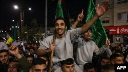 FILE —Palestinians prisoners (wearing grey jumpers) cheer among supporters after being released from Israeli jails in exchange for hostages released by Hamas from the Gaza Strip, in Ramallah in the occupied West Bank early on November 26, 2023.