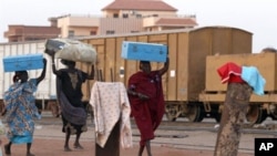 Southern Sudanese women carry their luggage as they prepare to board a train in Khartoum on January 9, 2011 on their way to the south
