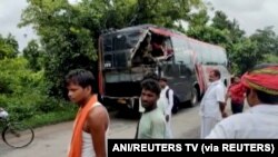 Orang-orang berdiri di lokasi kecelakaan setelah sebuah truk yang melaju kencang menabrak bus tingkat yang penuh sesak, di distrik Barabanki, Uttar Pradesh, India, 28 Juli 2021. (Foto: ANI/REUTERS TV via REUTERS)
