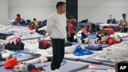 Ronny, a 26-year-old asylum-seeker from Venezuela, stands for a Catholic Mass celebrated by visiting priests in the large room where migrants rest and sleep at the Humanitarian Respite Center in McAllen, Texas, on Dec. 15, 2022.
