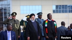 Iranian President Ebrahim Raisi is welcomed by his Zimbabwean counterpart Emmerson Mnangagwa, at Robert Mugabe International Airport in Harare, July 13, 2023.