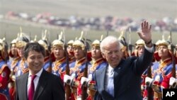 U.S. Vice President Joe Biden, right, waves as he walk with Mongolian Prime Minister Batbold Sukhbaatar after they inspected honor of guards upon arrival at the Chinggis Khaan International Airport in Ulan Bator, Mongolia, August 22, 2011