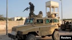 FILE - A soldier serving in the African Union Mission in Somalia (AMISOM) prepares to jump off a military vehicle near the scene of a suicide bombing targeting an AMISOM convoy in Mogadishu, Nov. 11, 2021. 