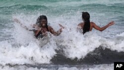 Women enjoy the waves from a high surf, July 31, 2020, in Miami Beach, Fla. 
