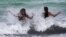 Women enjoy the waves from a high surf, July 31, 2020, in Miami Beach, Fla. 