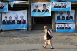 An Afghan man walks past election posters on the outskirts of Kabul, Afghanistan, Sept. 23, 2019.