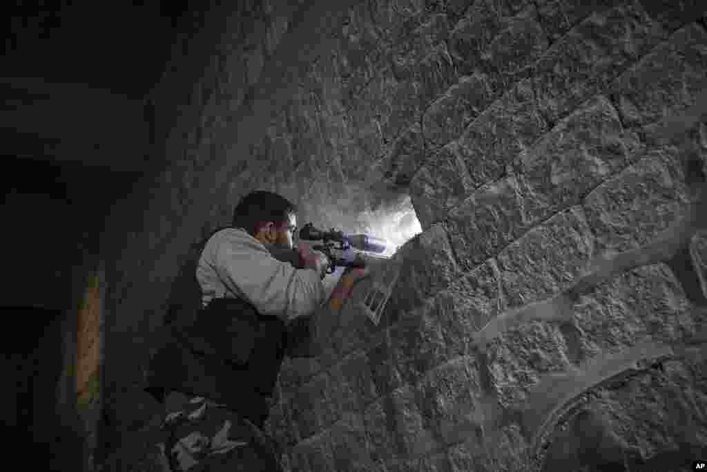 A rebel sniper aims through a hole in the wall that overlooks a position held by Syrian troops during heavy clashes in the Jedida district of Aleppo, Syria. Nov. 4