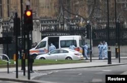 FILE - Police work at Carriage Gate outside the Houses of Parliament the morning after an attack by a man driving a car and weilding a knife left five people dead and dozens injured, in London, Britain, March 23, 2017.