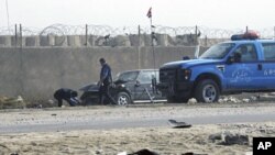 People prepare to tow away a car damaged by a suicide car bomb explosion in the Iraqi town of Taji, north of Baghdad, Nov. 28, 2011