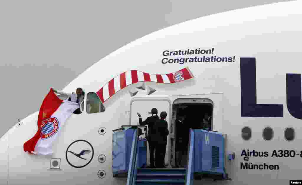 The pilot of an A380 aircraft carrying the Bayern Munich soccer players, waves a flag in team colors from a window of the plane on arrival at Munich airport, Germany, the day after Bayern Munich won the Champions League final soccer match at Wembley stadium in London.