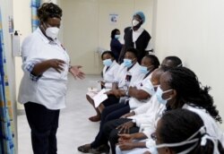 FILE - A health worker talks to colleagues as they prepare to receive a coronavirus vaccine at the Kenyatta National Hospital in Nairobi, Kenya, March 5, 2021.