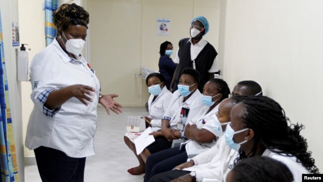 FILE - A health worker talks to colleagues as they prepare to receive a coronavirus vaccine at the Kenyatta National Hospital in Nairobi, Kenya, March 5, 2021.