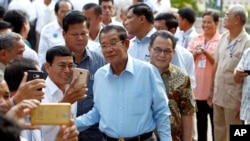 Cambodian Prime Minister Hun Sen, center, of ruling Cambodian People's Party pose for a selfie with his party supporters after a voting in the Senate election at Takhmau polling station in Kandal province, southeast of Phnom Penh, Cambodia, Sunday, Feb. 25, 2018. Cambodia's ruling party is assured of a sweeping victory in the election of a new Senate after the only real opposition to it was eliminated. (AP Photo/Heng Sinith)