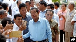 Cambodian Prime Minister Hun Sen, center, of ruling Cambodian People's Party, poses for a selfie with his party supporters after a voting in the Senate election at Takhmau polling station in Kandal province, southeast of Phnom Penh, Cambodia, Sunday, Feb. 25, 2018. Cambodia's ruling party is assured of a sweeping victory in the election of a new Senate after the only real opposition to it was eliminated. (AP Photo/Heng Sinith)