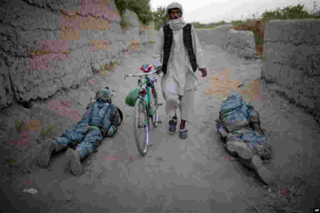 An Afghan villager walks among US soldiers from L Trp 4/25CR at a check point in Kandahar City, Afghanistan, Thursday, Oct. 21, 2010. (AP Photo/Rodrigo Abd)