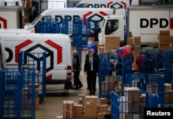 FILE - Britain's Chancellor of the Exchequer George Osborne walks past delivery vans during a visit to the DPD parcels depot in Raunds, Britain, May 6, 2015.