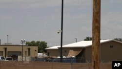 FILE - National Guard soldiers adjust a shade tarp over portable toilets by a building used for the detention of migrant children in Border Patrol custody in Clint, Texas, June 26, 2019. 