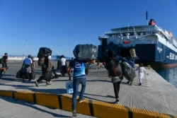 Refugees and Migrants disembark on a ferry with destination the port of Piraeus, on the northeastern Aegean island of Lesbos, Greece, Sept. 30, 2019.