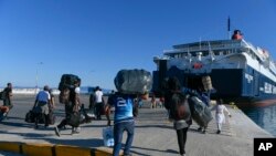 Refugees and Migrants disembark on a ferry with destination the port of Piraeus, on the northeastern Aegean island of Lesbos, Greece, Sept. 30, 2019. 