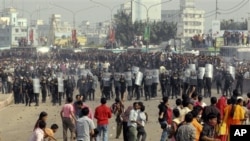 Protesting Bangladeshi garment workers throw stones at police near the international airport in Dhaka, Bangladesh, Sunday, Dec. 12, 2010. They were demanding the implementation of a new minimum wage.