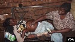 Mama Atoti massaging a pregnant woman belly, using Arimis - a popular petroleum jelly commonly used by farmers to apply on their hands before milking cows, Nairobi, June 18, 2016. (R. Ombour/VOA)