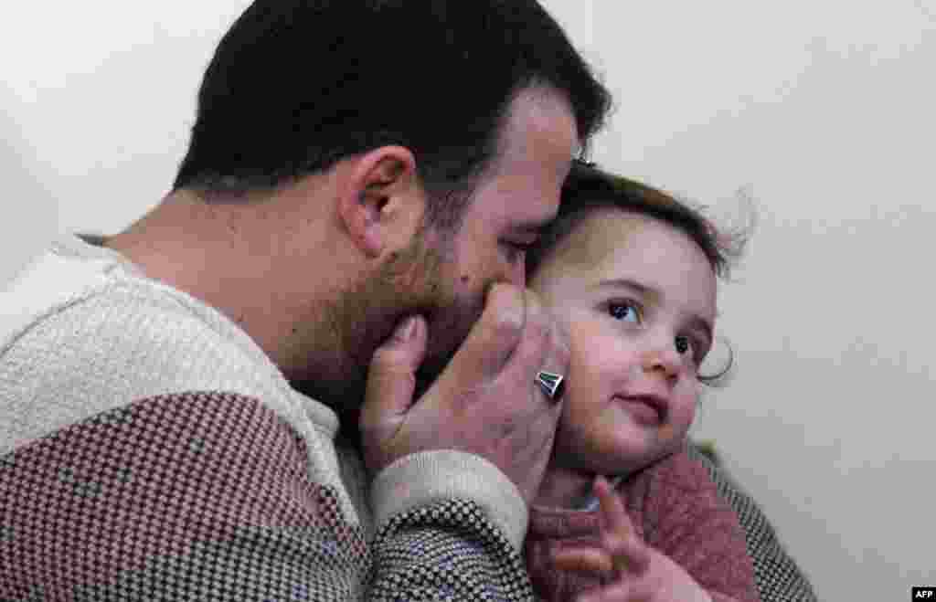 Syrian father Abdullah al-Mohammed whispers on the ear of his three-year-old daughter Salwa at their home in Sarmada, a town in Syria&#39;s last rebel pocket in the Idlib province, which Russian-backed Syrian regime forces are trying to crush. Abdullah said the only way he found to reassure his daughter Salwa was to turn the shelling into a game.