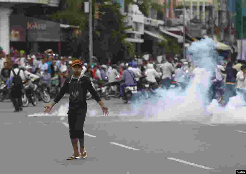 A protester supporting the opposition Cambodia National Rescue Party reacts as police fire tear gas during clashes near the Royal Palace in Phnom Penh. Sept. 15, 2013. 