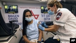 A medic with Israel's Magen David Adom emergency service administers a booster shot of a COVID-19 vaccine to a woman in Tel Aviv, Aug. 14, 2021. 